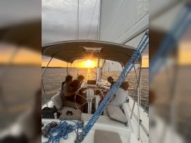 A group enjoys a beautiful sunset while sailing, creating a perfect atmosphere for relaxation and celebration on the water.