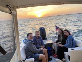 A cheerful group enjoys a sunset cruise on a boat, capturing the perfect moment of relaxation and camaraderie on the water.