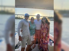 A cheerful group poses for a photo on a boat at sunset, capturing a memorable family outing on the water.