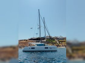 A sleek catamaran named 'Proteas' docked in calm waters, showcasing its elegant design against a clear blue sky — perfect for luxury sailing experiences.