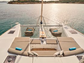 A beautifully arranged lounge area on a catamaran, featuring comfortable seating and a serene view of the water, perfect for relaxation while cruising.