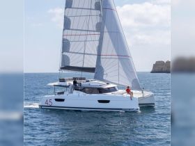 A sleek catamaran sails through clear waters, showcasing a perfect day on the water with guests enjoying the ride.