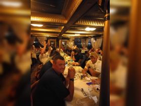 Guests enjoy a lively dining experience inside a boat restaurant, showcasing a vibrant atmosphere perfect for group gatherings.