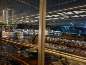 A reflective view from inside a boat, showcasing city lights and water, but the image lacks clarity and focus.