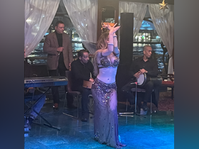 A captivating belly dancer performs aboard a boat, accompanied by live musicians, creating an unforgettable entertainment experience on the water.