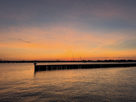 A stunning sunset casts vibrant colors over the water, creating a picturesque harbor scene — perfect for evening boat trips or romantic getaways.