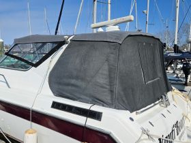 A close-up view of a boat's exterior featuring a covered helm area, docked at the marina. Ideal for showcasing boat features and design.