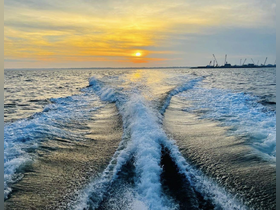 A stunning sunset view over the water, showcasing the wake of a boat in motion — perfect for capturing the beauty of evening cruises.