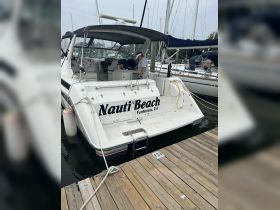A well-maintained yacht named 'Nauti Beach' docked at the marina, showcasing its spacious rear deck and inviting atmosphere.