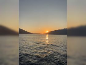 A stunning sunset over the mountains, reflecting on the calm waters — a perfect backdrop for evening boat cruises.