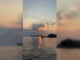 A stunning sunset casts reflections on the calm waters, creating a picturesque scene ideal for romantic evening cruises or serene getaways.