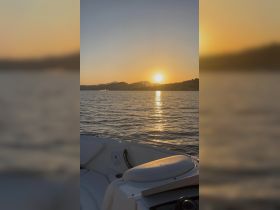 A serene sunset view from the deck of a boat, showcasing the tranquil waters and distant mountains — perfect for evening cruises.