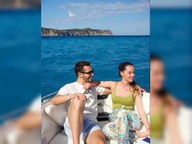 A couple enjoys a sunny day on a boat, smiling and relaxing against a stunning ocean backdrop — perfect for romantic getaways or fun outings on the water.