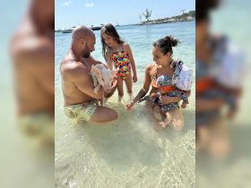 A family enjoys a unique experience swimming with a pig in shallow waters, creating unforgettable memories in a tropical paradise.