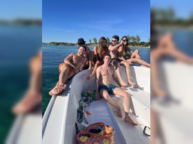 A lively group of friends enjoys a sunny day on a boat, capturing the essence of fun and relaxation on the water.