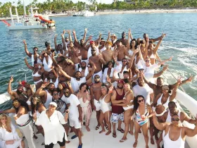 A vibrant group of party-goers celebrates aboard a boat, showcasing a lively atmosphere perfect for summer gatherings and events on the water.