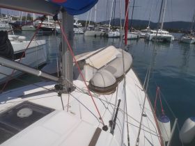 A close-up view of a sailboat's deck, showcasing its rigging and equipment while docked among other vessels.