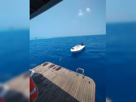 A clear view of a small boat anchored in vibrant blue waters, showcasing the serene beauty of the ocean environment.