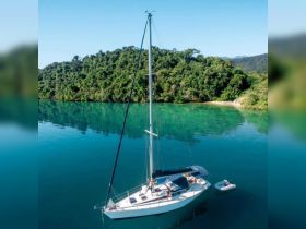 An aerial view of a sailboat anchored in tranquil waters, with guests enjoying the serene surroundings — a perfect setting for relaxation and adventure.