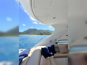 A stylish interior view of a yacht's lounge area, featuring plush seating and a scenic backdrop of the coastline — perfect for relaxing on the water.