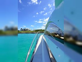 A stunning side view of a yacht gliding through crystal-clear turquoise waters, showcasing the beautiful landscape in the background — perfect for luxury boating experiences.
