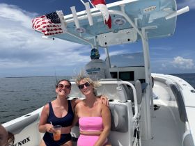Two friends enjoy cocktails and smiles aboard a boat, capturing the essence of fun and relaxation on the water.