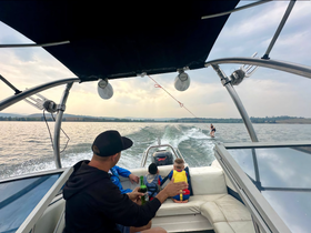 A family enjoys a thrilling day on the water, with a child watching as someone water skis behind the boat — a perfect blend of fun and adventure.