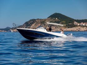 A speedboat glides through calm waters with passengers enjoying the ride, set against a stunning coastal backdrop — perfect for adventure seekers and scenic tours.