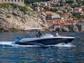 A couple enjoys a scenic boat ride along the stunning coastline, with picturesque buildings in the background, perfect for exploring beautiful destinations.