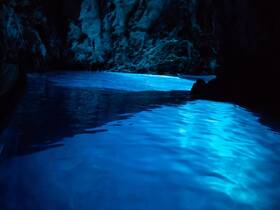 A stunning view of glowing blue waters inside a cave, showcasing the natural beauty of this unique destination — perfect for eco tours and scenic boat trips.