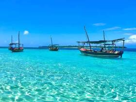 A picturesque view of traditional boats anchored in crystal-clear turquoise waters, showcasing the beauty of a tropical paradise.