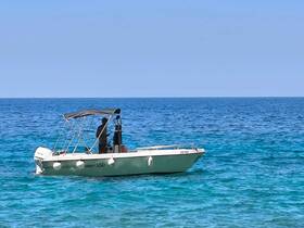 A lone figure operates a boat in the clear blue waters, showcasing a serene day on the sea — perfect for fishing or exploring coastal areas.