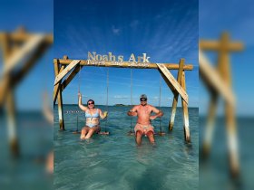 A couple enjoys swinging in the shallow waters of Turks and Caicos, sipping cocktails and soaking up the sun — a perfect beach getaway experience.