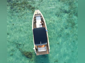 Aerial view of a couple relaxing on a stylish boat in crystal-clear waters, perfect for a serene day on the water.
