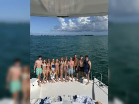 A lively group of friends enjoys a day on the water, posing on the deck of a boat, perfect for summer celebrations and fun in the sun.