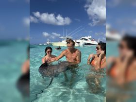 A thrilling encounter as guests interact with a stingray in crystal-clear waters, showcasing the unique wildlife experiences available during boat tours.