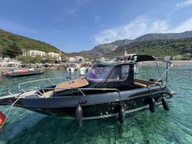 A sleek black boat docked in clear waters, surrounded by a scenic coastal backdrop — perfect for exploring beautiful destinations.