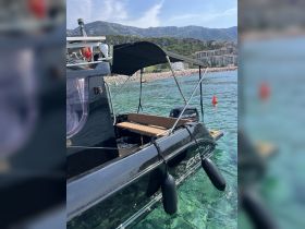 A sleek black boat anchored in clear waters, showcasing its design and surroundings, perfect for exploring coastal destinations.