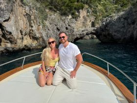 A couple poses on the bow of a boat, surrounded by stunning rock formations and clear waters — a perfect moment for romantic getaways or scenic tours.