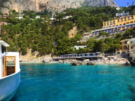 A picturesque view of a vibrant beach scene with a boat in the foreground, showcasing the stunning coastline and clear turquoise waters — perfect for island adventures.