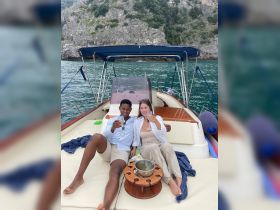 A couple enjoys a toast with cocktails on the deck of a boat, surrounded by stunning coastal scenery — perfect for romantic getaways or special celebrations.