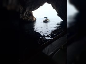 A boat navigates through a stunning cave entrance, showcasing the beauty of marine exploration and adventure.