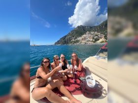 A group of friends celebrates with cocktails aboard a yacht, enjoying the stunning coastal views — perfect for memorable summer outings.