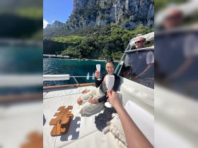 Guests enjoy a toast with cocktails aboard a yacht, surrounded by stunning coastal scenery — perfect for celebrations and memorable outings on the water.