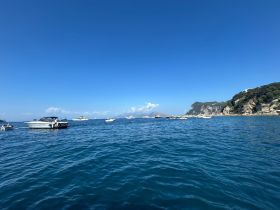 A scenic view of various boats anchored in clear blue waters, showcasing the beauty of a coastal landscape.