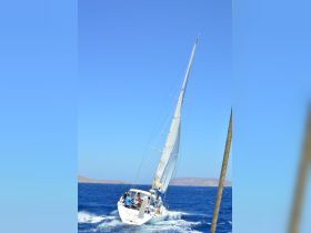 A dynamic shot of a sailboat navigating through vibrant blue waters, showcasing the thrill of sailing with crew members on board.