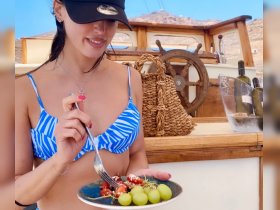 A woman enjoys a plate of fresh grapes and snacks aboard a boat, showcasing the perfect amenities for a relaxing day on the water.