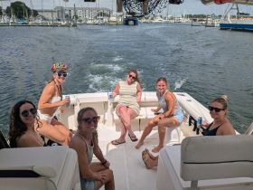 A lively group of friends enjoys a fun day on the boat, showcasing camaraderie and celebration on the water.