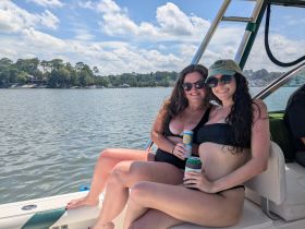 Two friends enjoy a sunny day on the water, sipping drinks and soaking up the sun — a perfect moment for summer boating adventures.