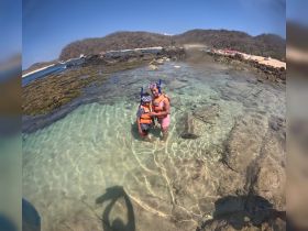 A mother and child enjoy snorkeling in clear waters, surrounded by rocky formations — a perfect family adventure in a tropical paradise.